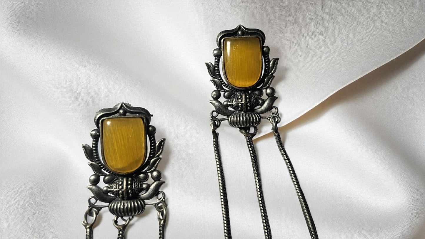 Pair of silver earrings with yellow gemstones on a white background
