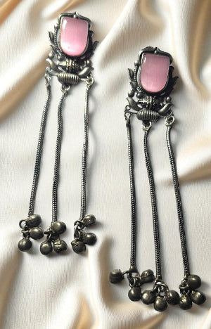 Pair of earrings with pink stones and black beads on a white fabric background